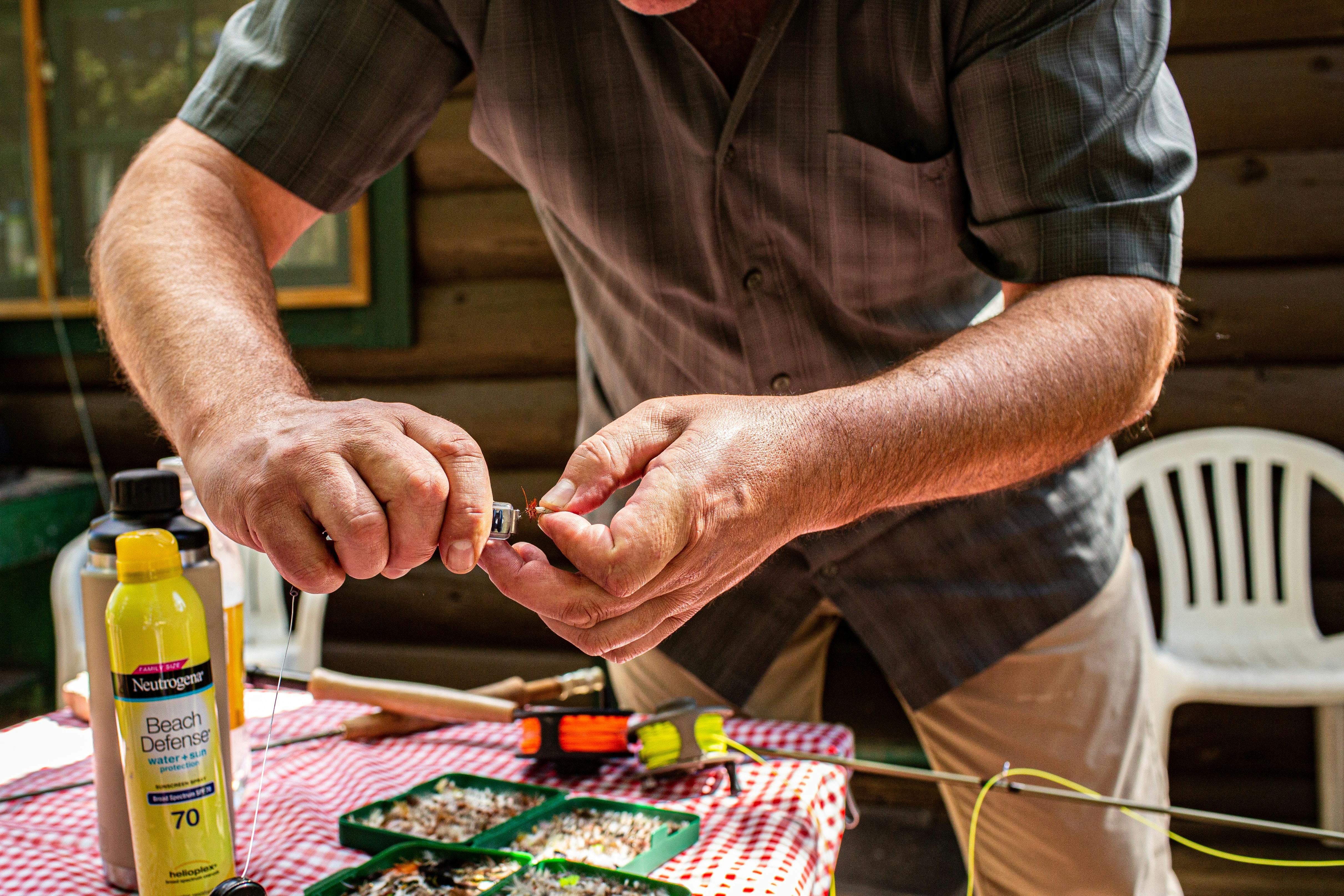 A man preparing gear indoors for a fly fishing outing