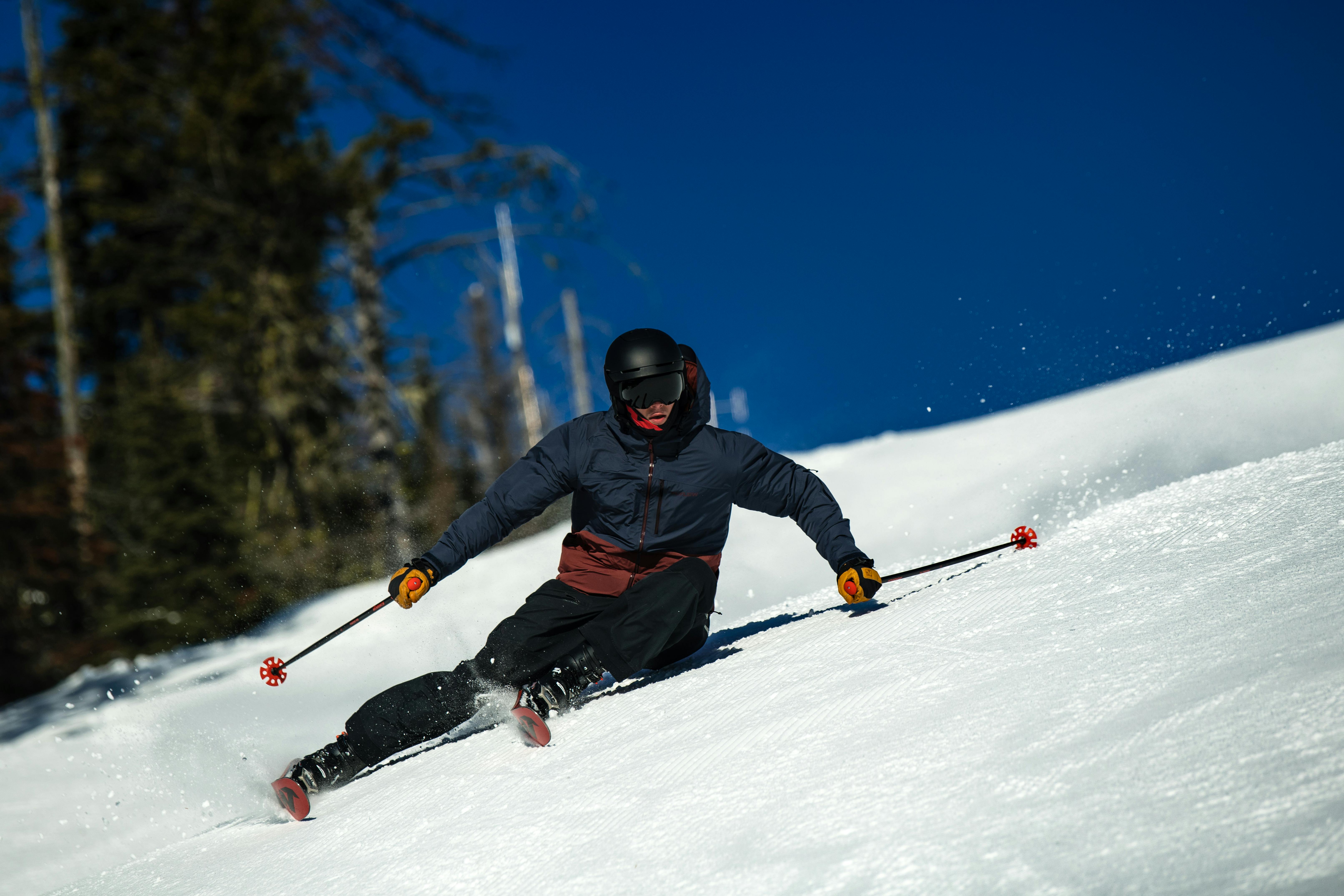 Man skiing down a steep slope wearing the Flylow Cobra Jacket.