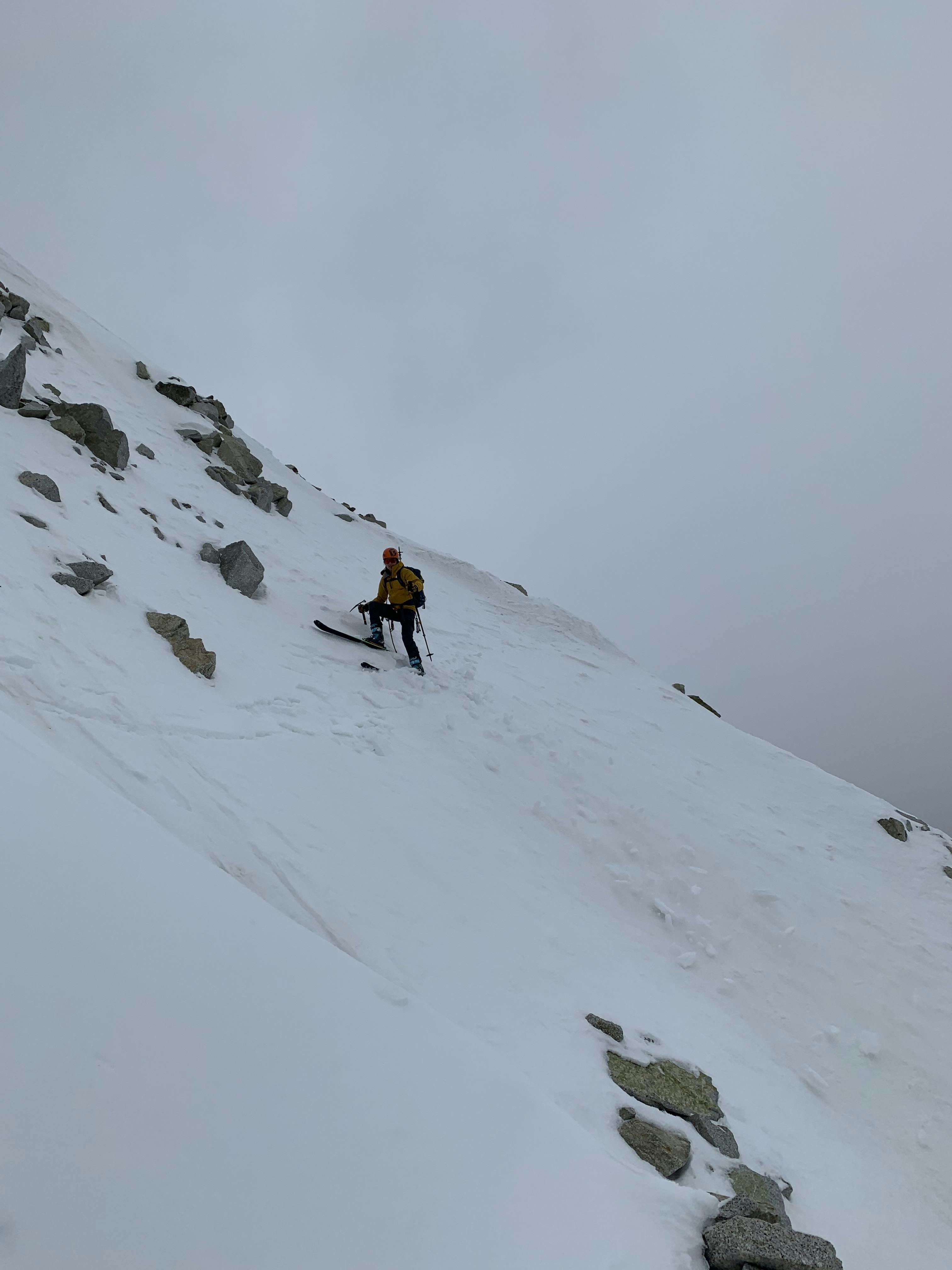 A skier at the top of a rocky snowfield.