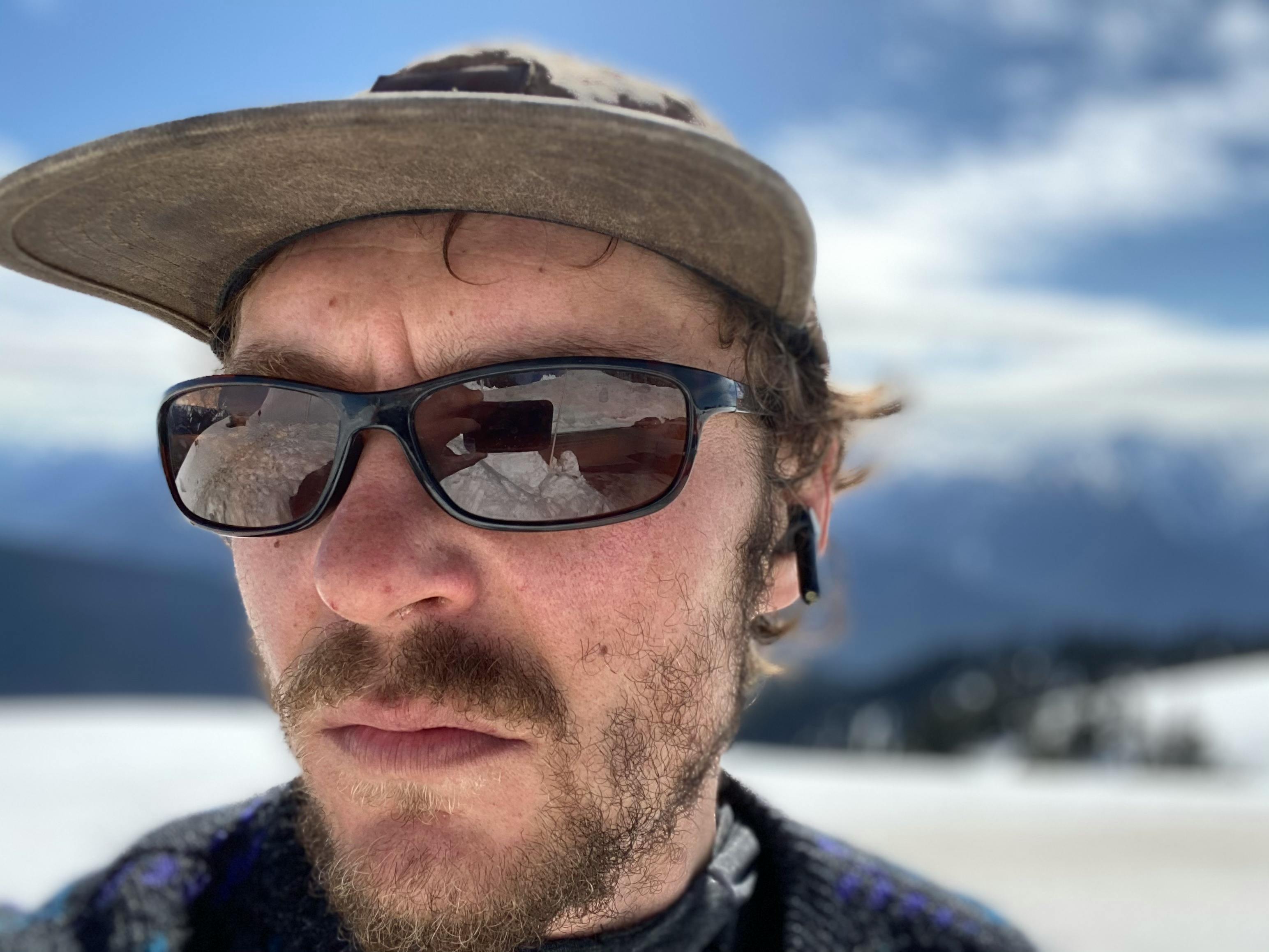 The author takes a selfie of him in a hat and sunglasses on the snow.