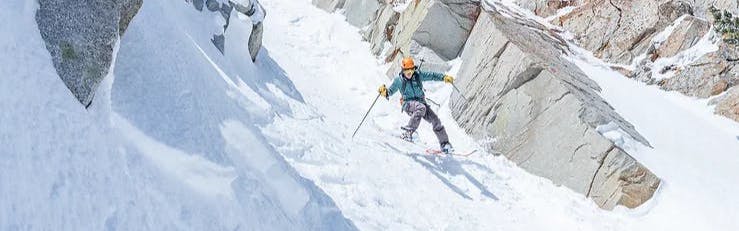 A man skiing down a chute with the La Sportiva Synchro AT 125 Ski Boots.