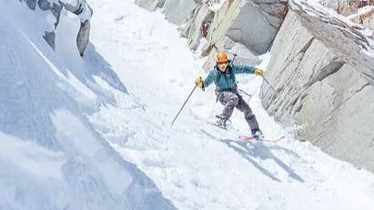 A man skiing down a chute with the La Sportiva Synchro AT 125 Ski Boots.