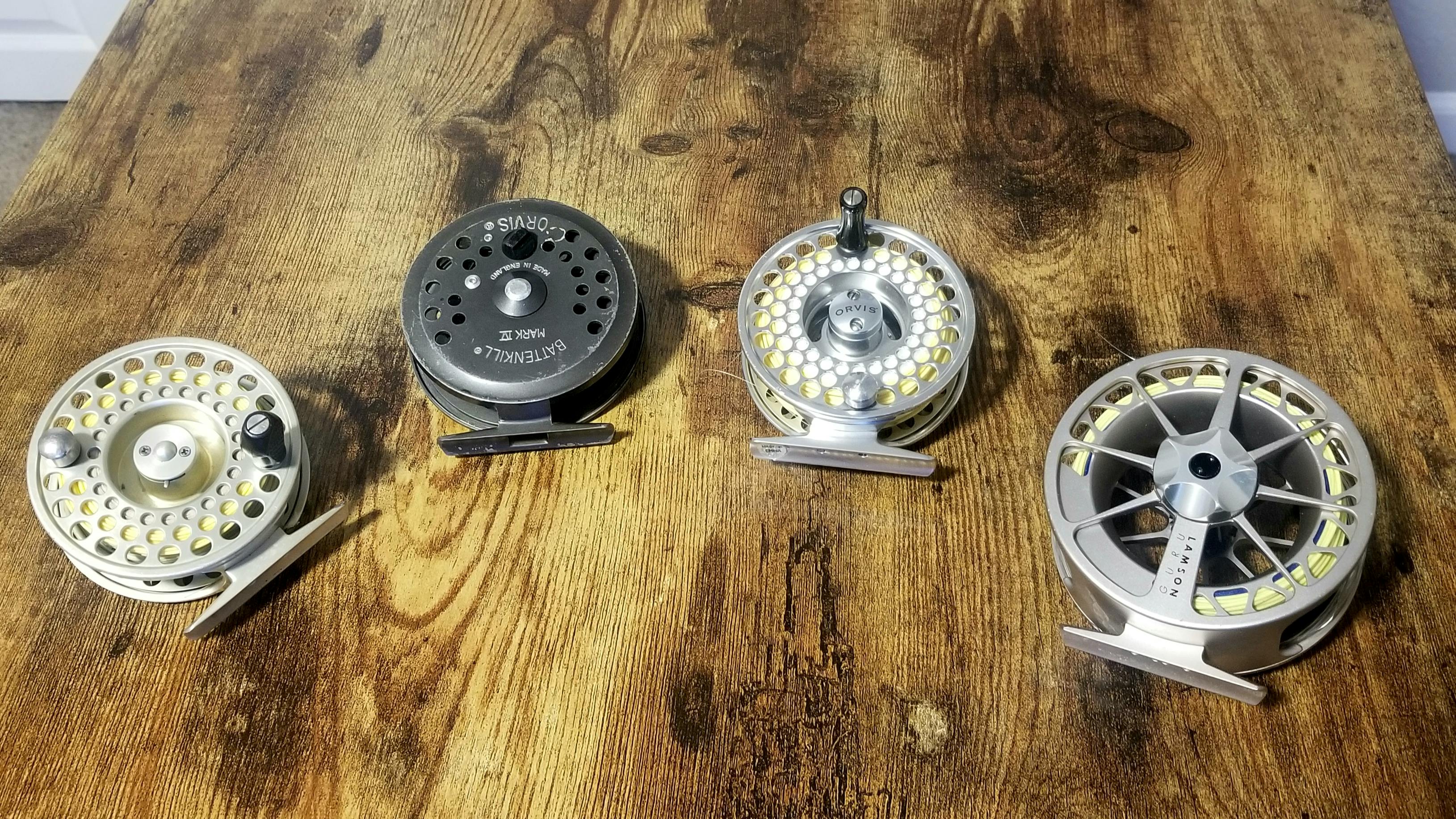 Four fly reels laying on a wooden table