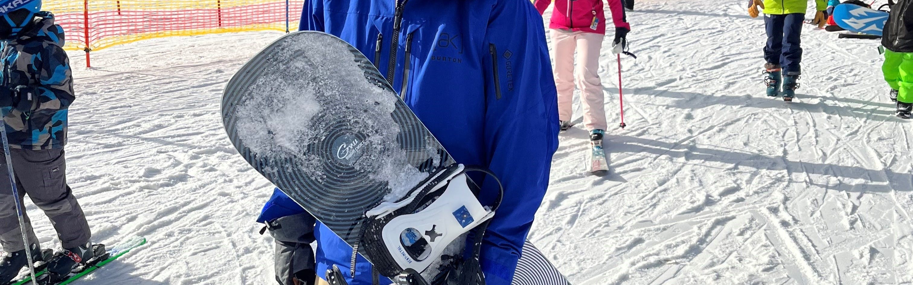 A man holding the GNU Riders Choice Snowboard · 2023.