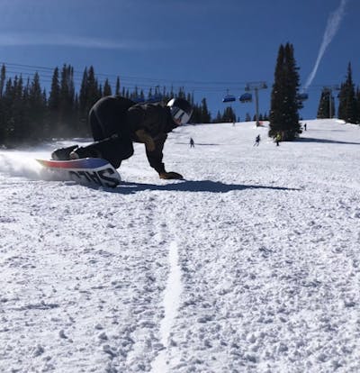 A snowboarder carving down a ski run. 
