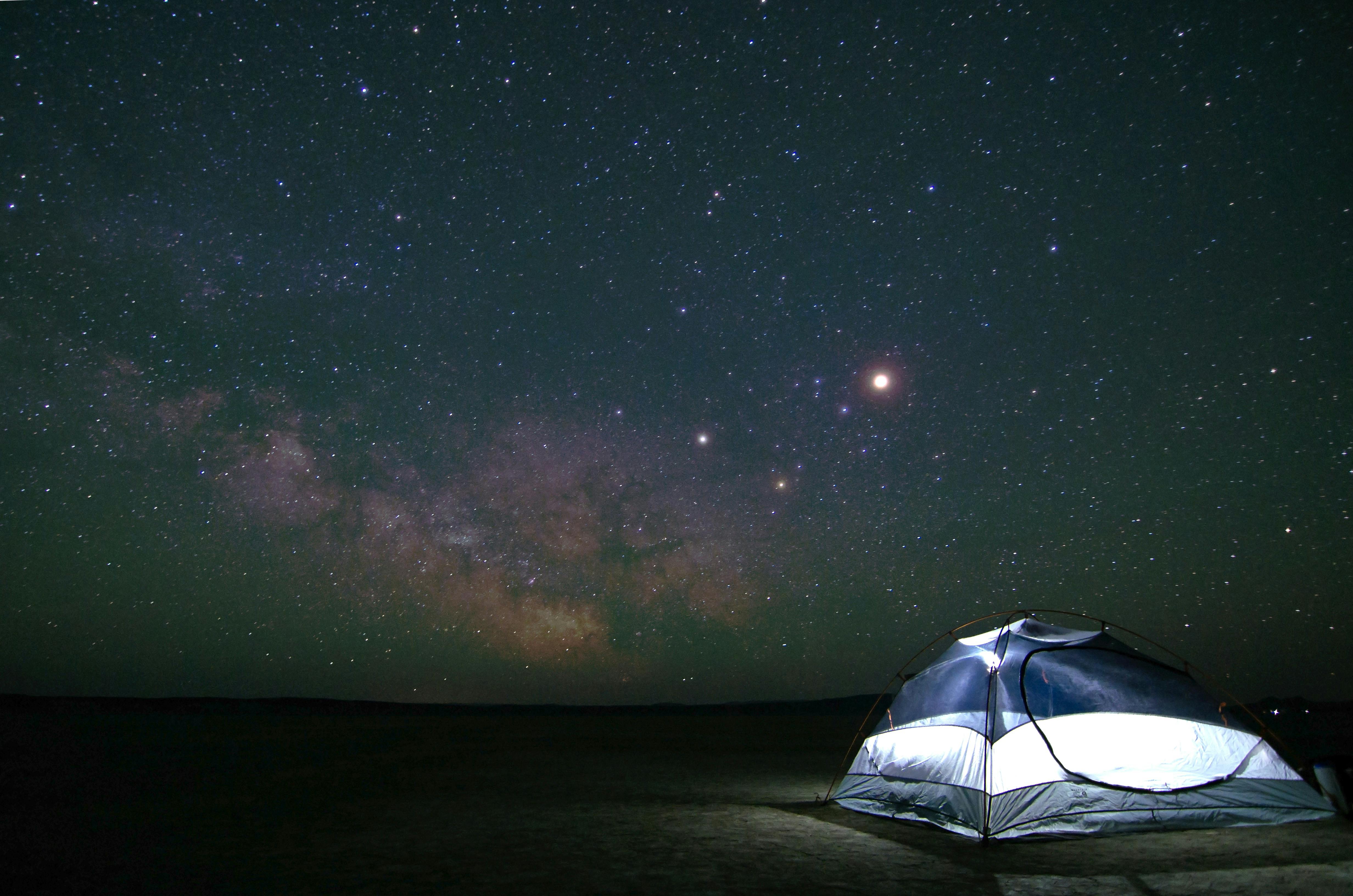 A tent glows with stars in the sky