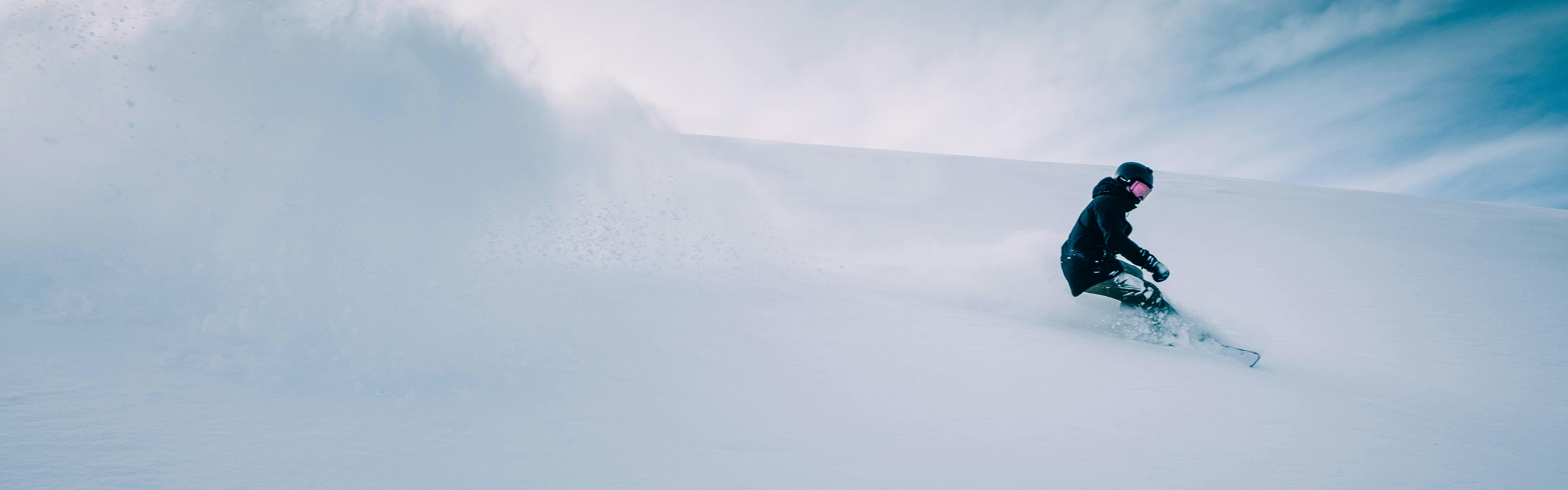 A snowboarder kicks up a cloud of powder as they turn