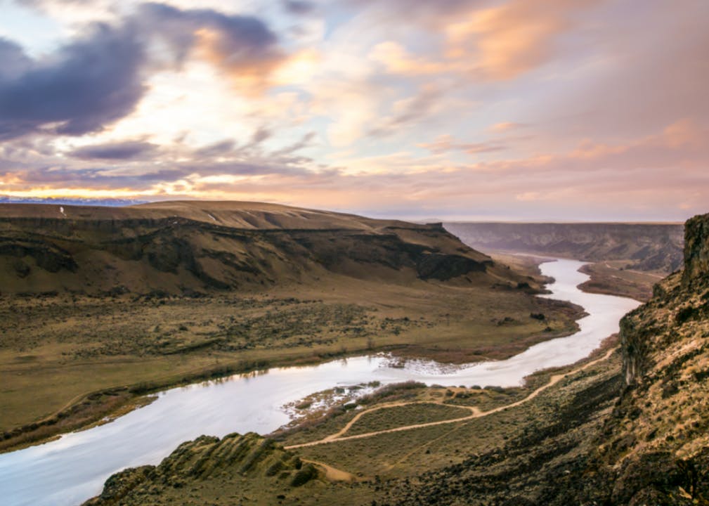 A river winding through a dry, hilly landscape at sunrise