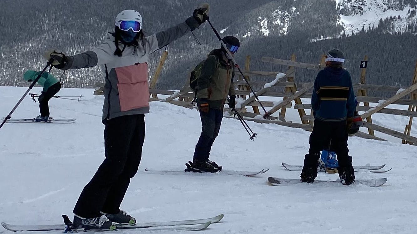 Three skiers stand on a ski trail. One of them is wearing the North Face Sally Pant.