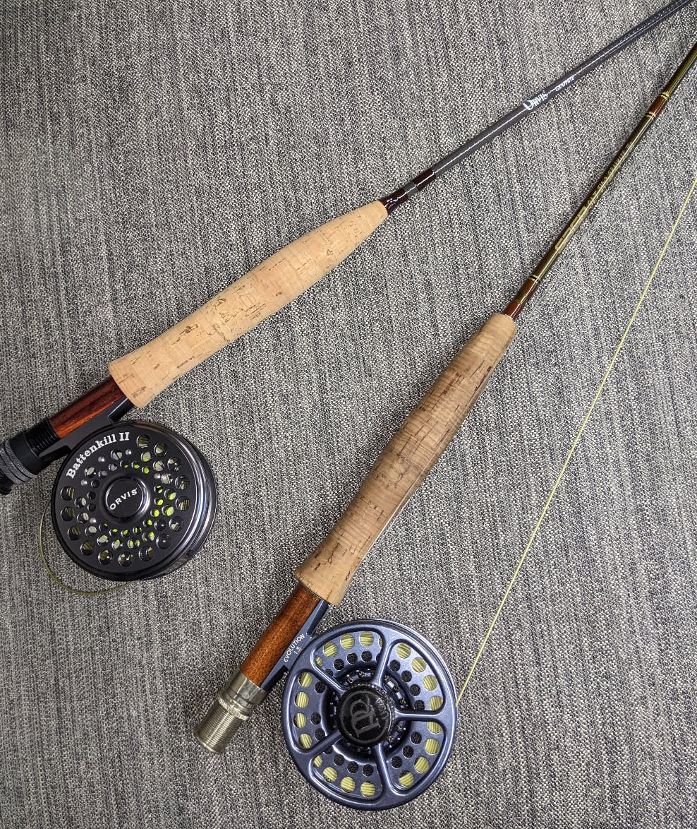Two fishing rods lay on the ground next to each other.