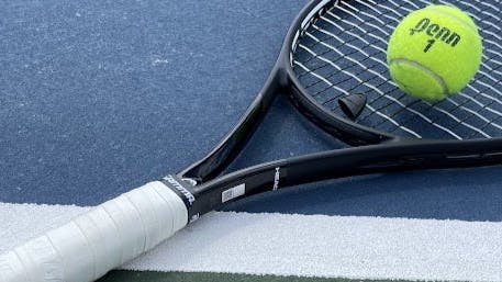 The Head speed MP racquet laying on a tennis court.