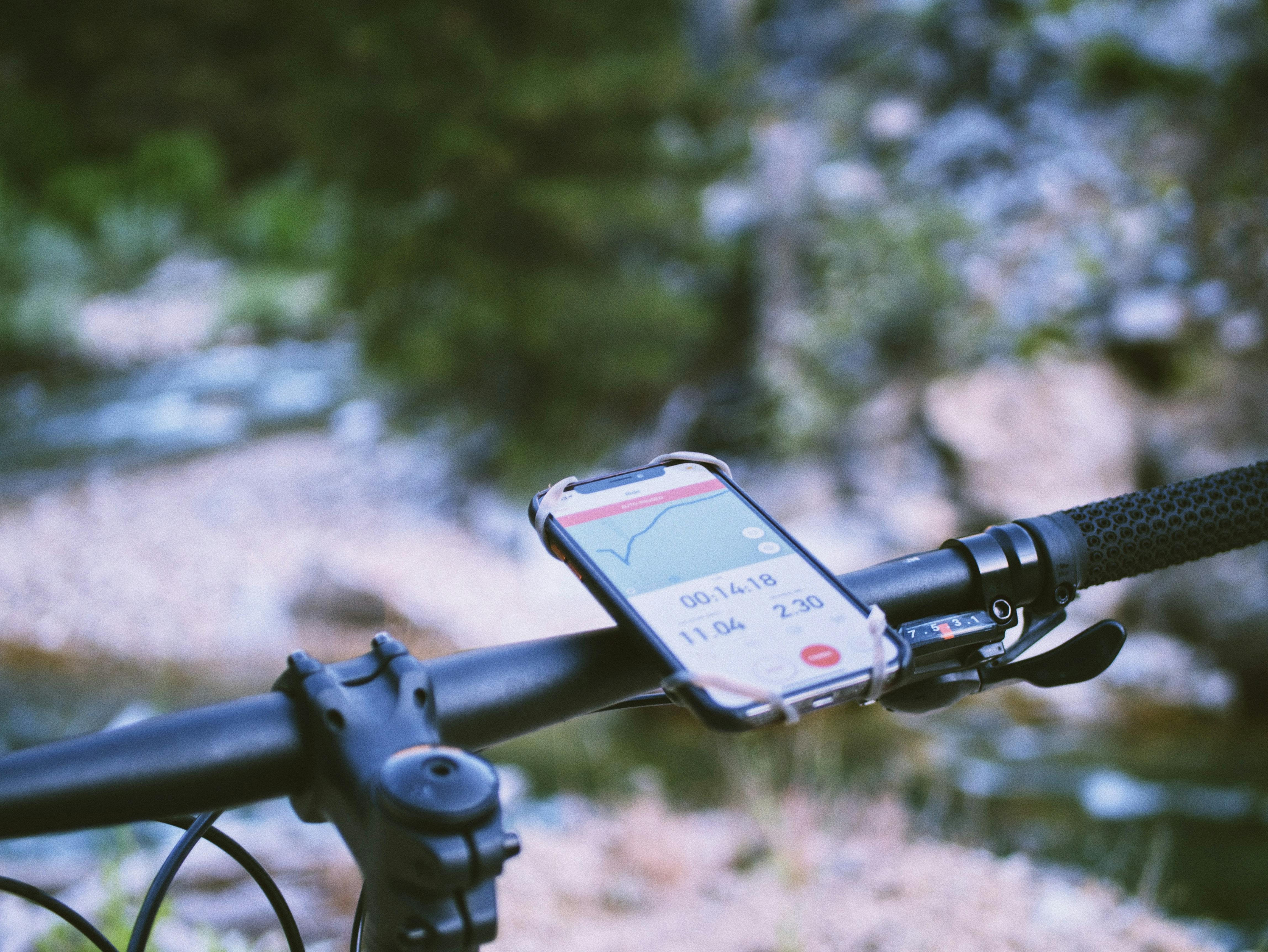 A map is pulled up on a phone and the phone is attached to the handlebars of a bike.