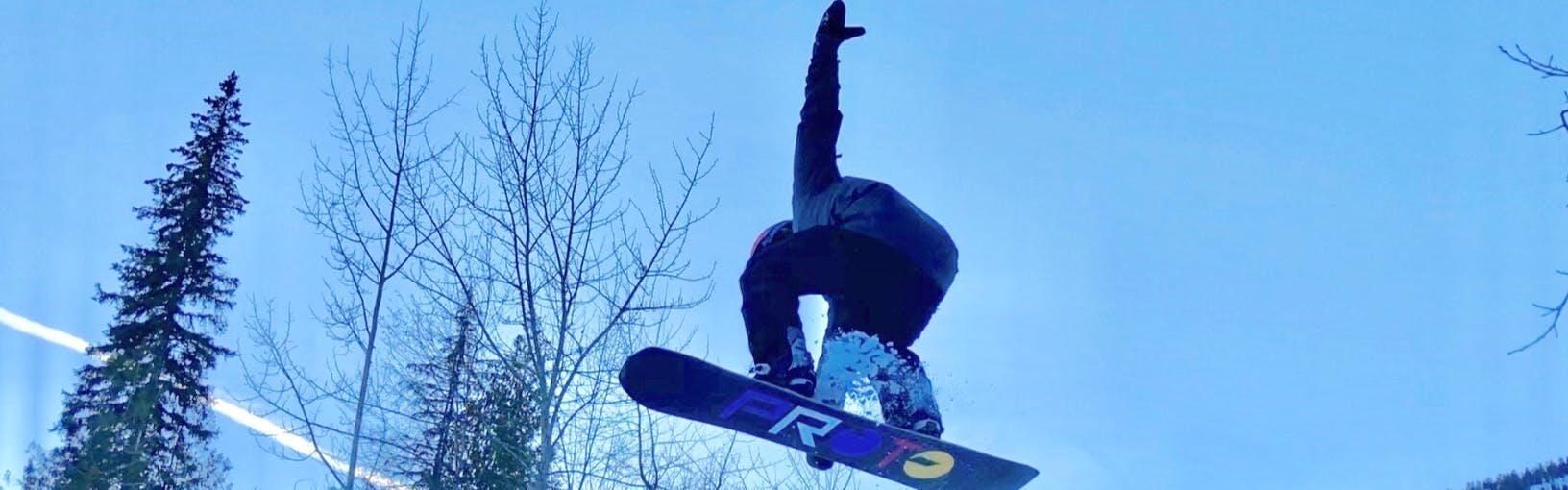Man on performing a snowboard jump trick in the air
