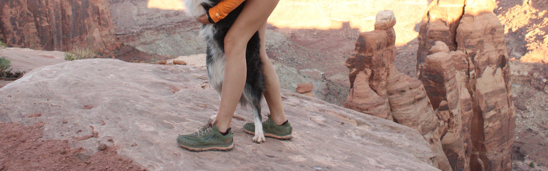 A pair of Altra Lone Peak 6's with some dog feet. There are red rocks in the background. 