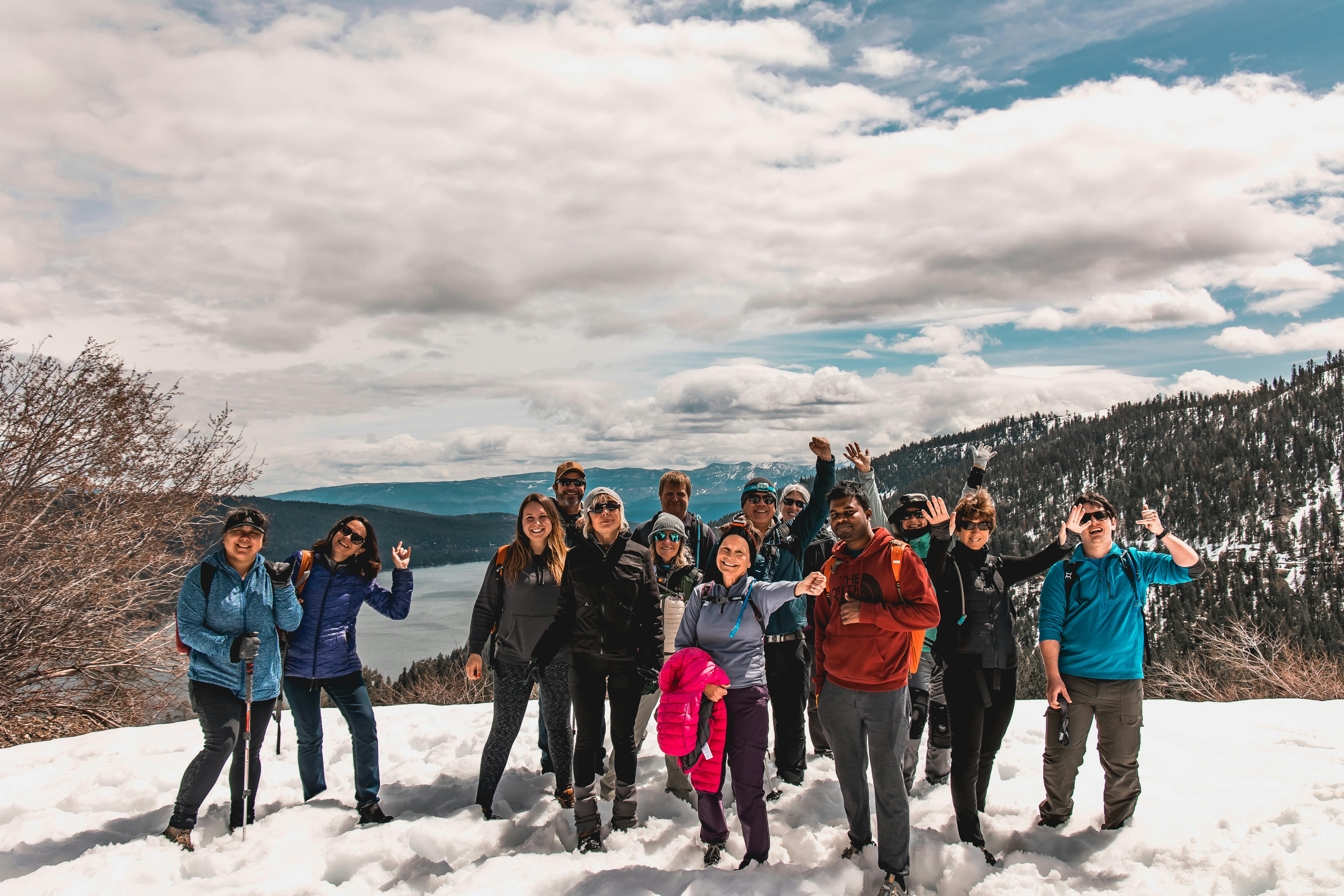 A group of people stand on a snowfield and smile for the camera while on a hike.