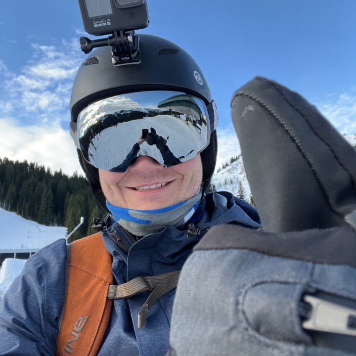 A skier wearing a helmet giving the camera a thumbs up with a Dakine Men's Titan GORE-TEX Glove. 