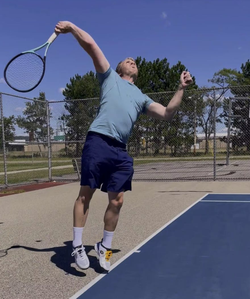 A man taking a tennis swing with the Head Boom MP.