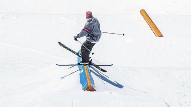 A skier hitting a rail on a pair of skis.