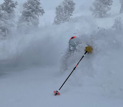 A pole and glove are barely visible from the deep powder that the skier is in.