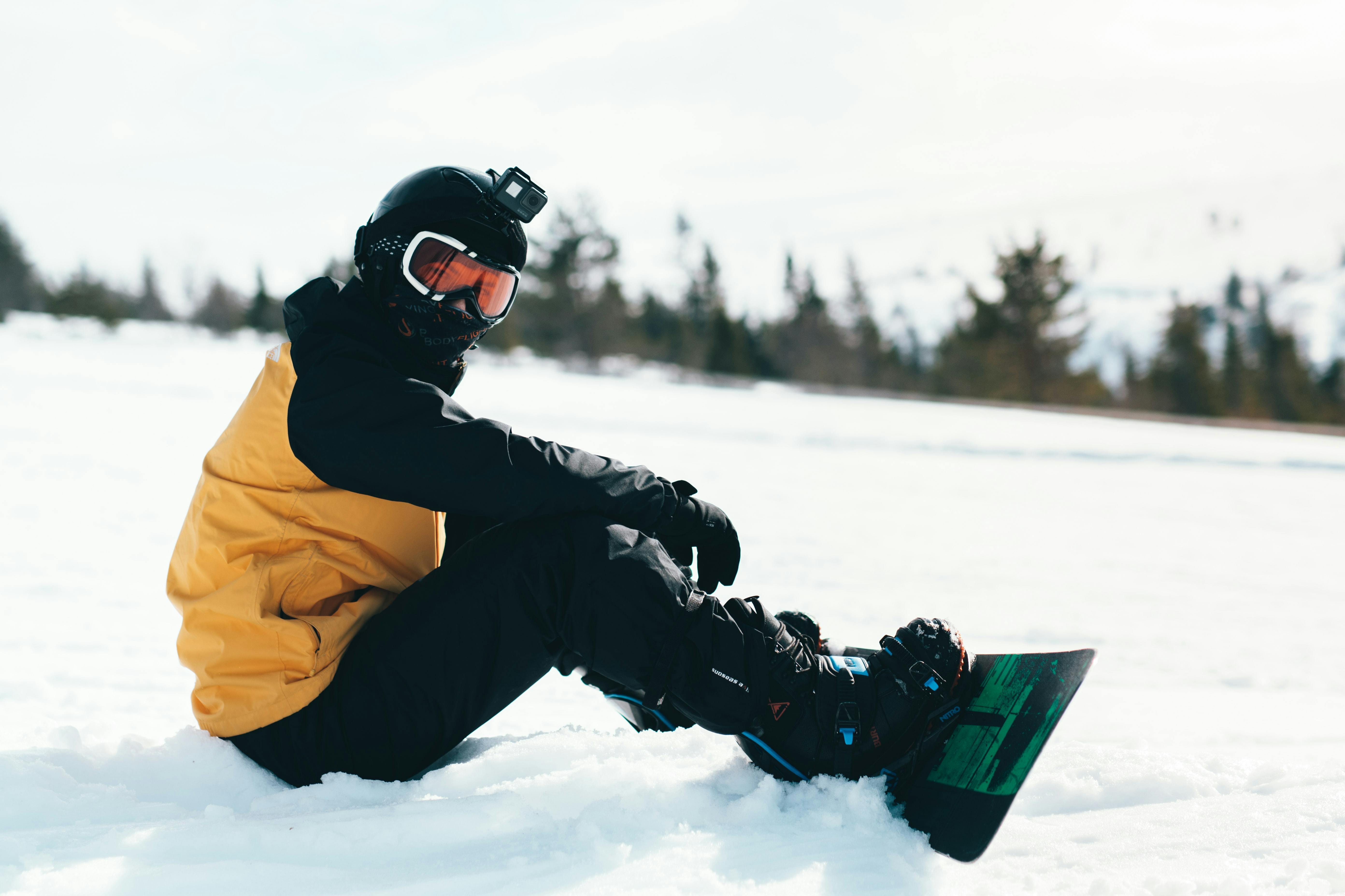 A snowboarder sits down on the snow with their snowboard still attached.