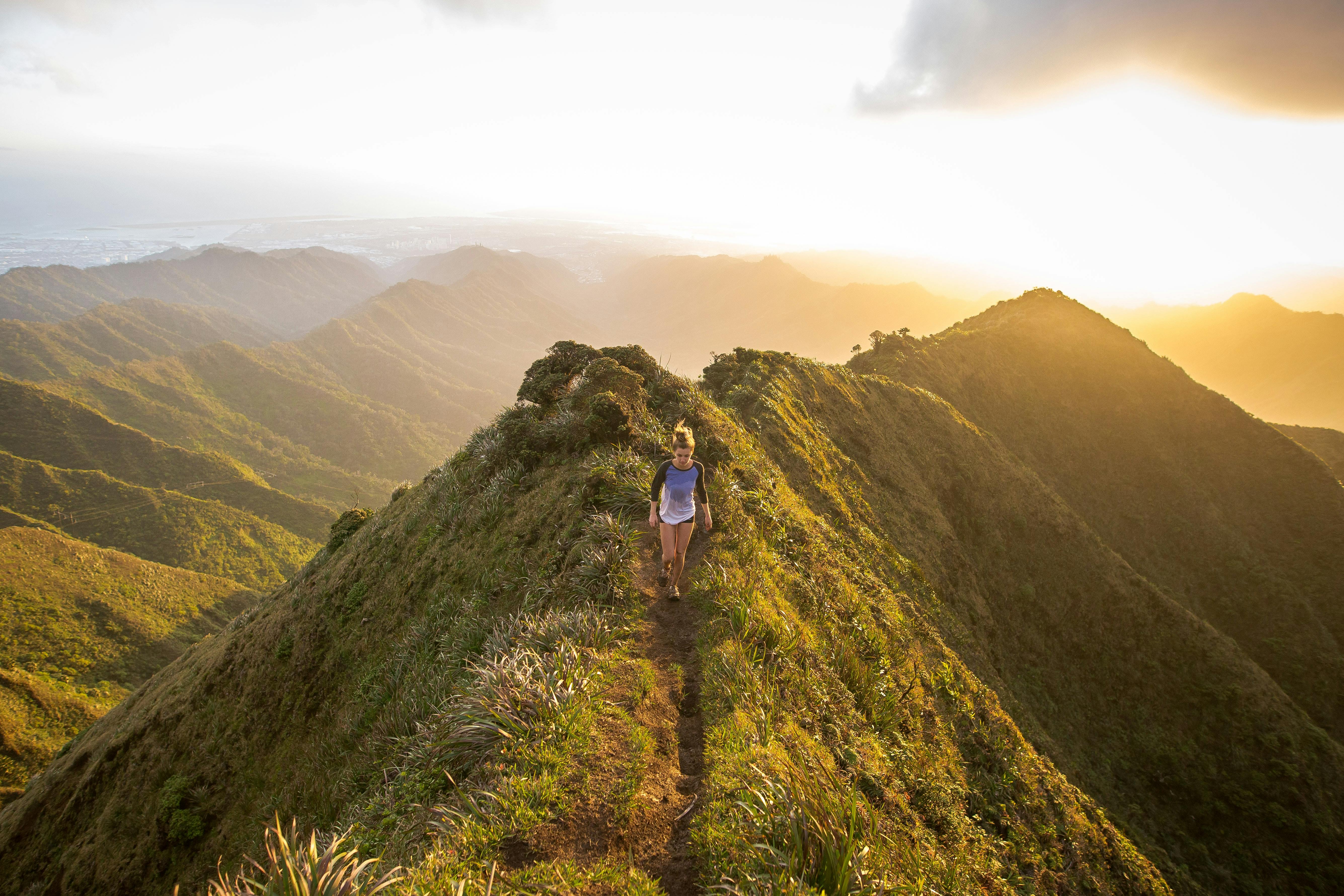 A woman on a trail with a beautiful backdrop of clouds and mountains. 