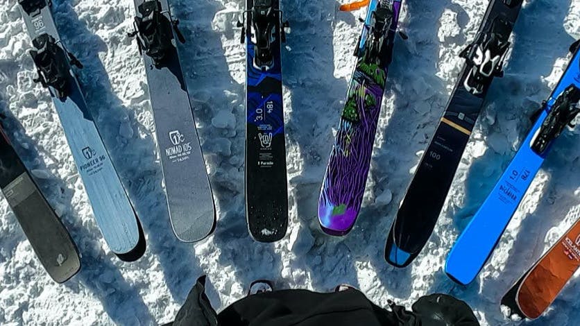 Top down view of several skis laying in the snow. 