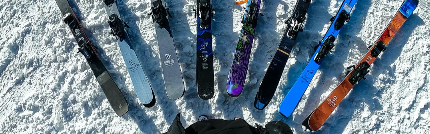 Top down view of several skis laying in the snow. 