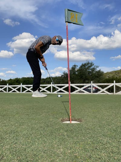 A man using the The Mizuno M.Craft Type III Putter to hit a golf ball.