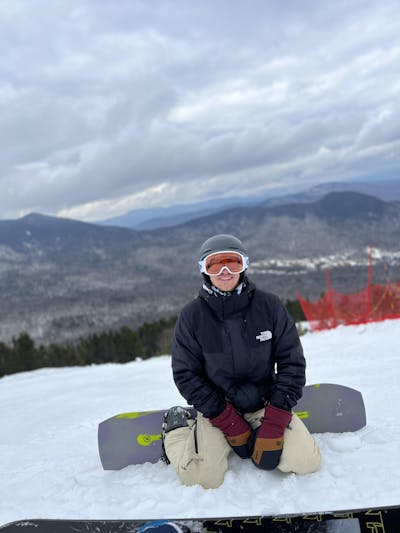 A snowboarder sitting in the snow on the Ride Warpig Snowboard.