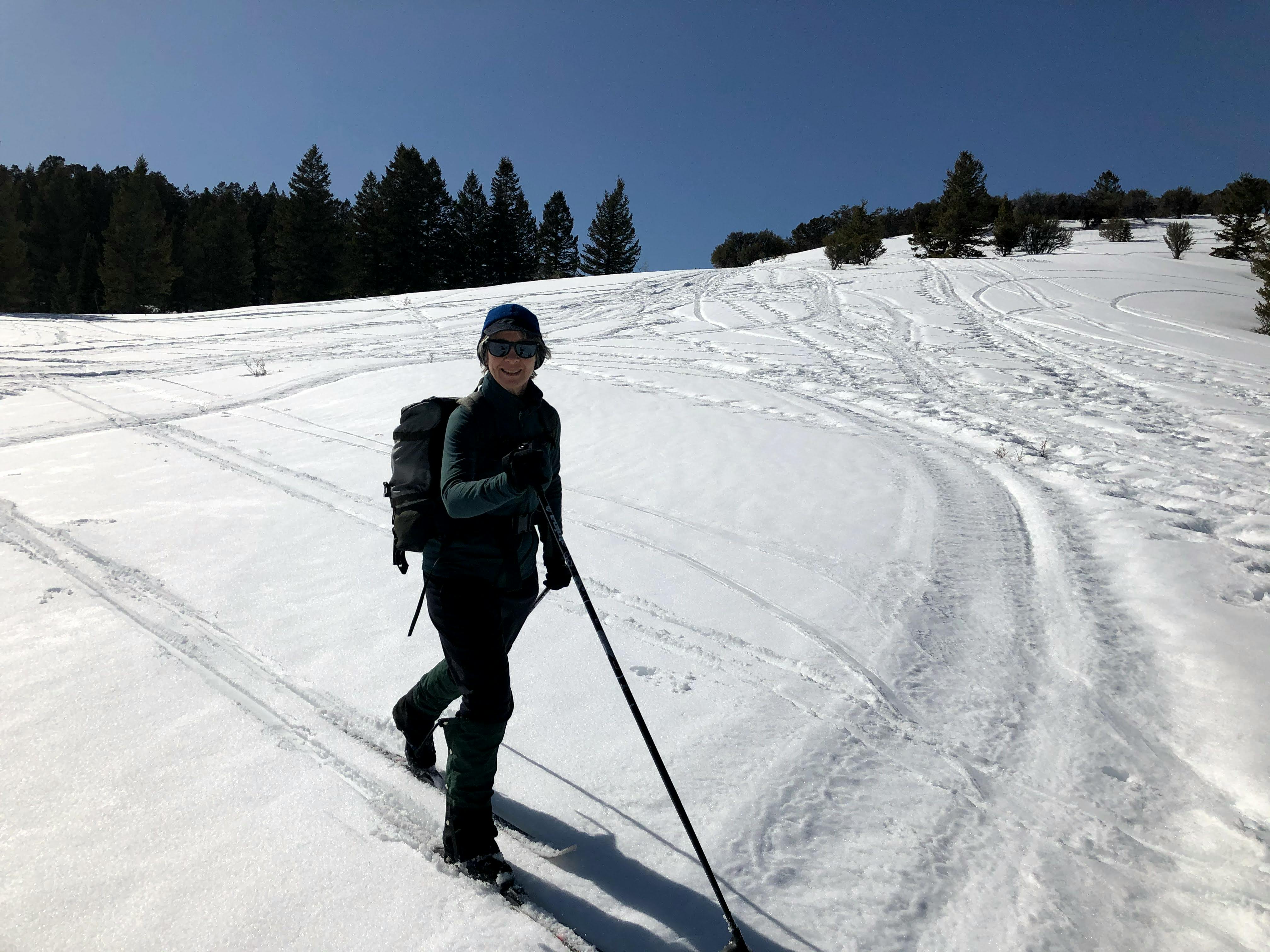 A woman on cross country skis smiles at the camera. 