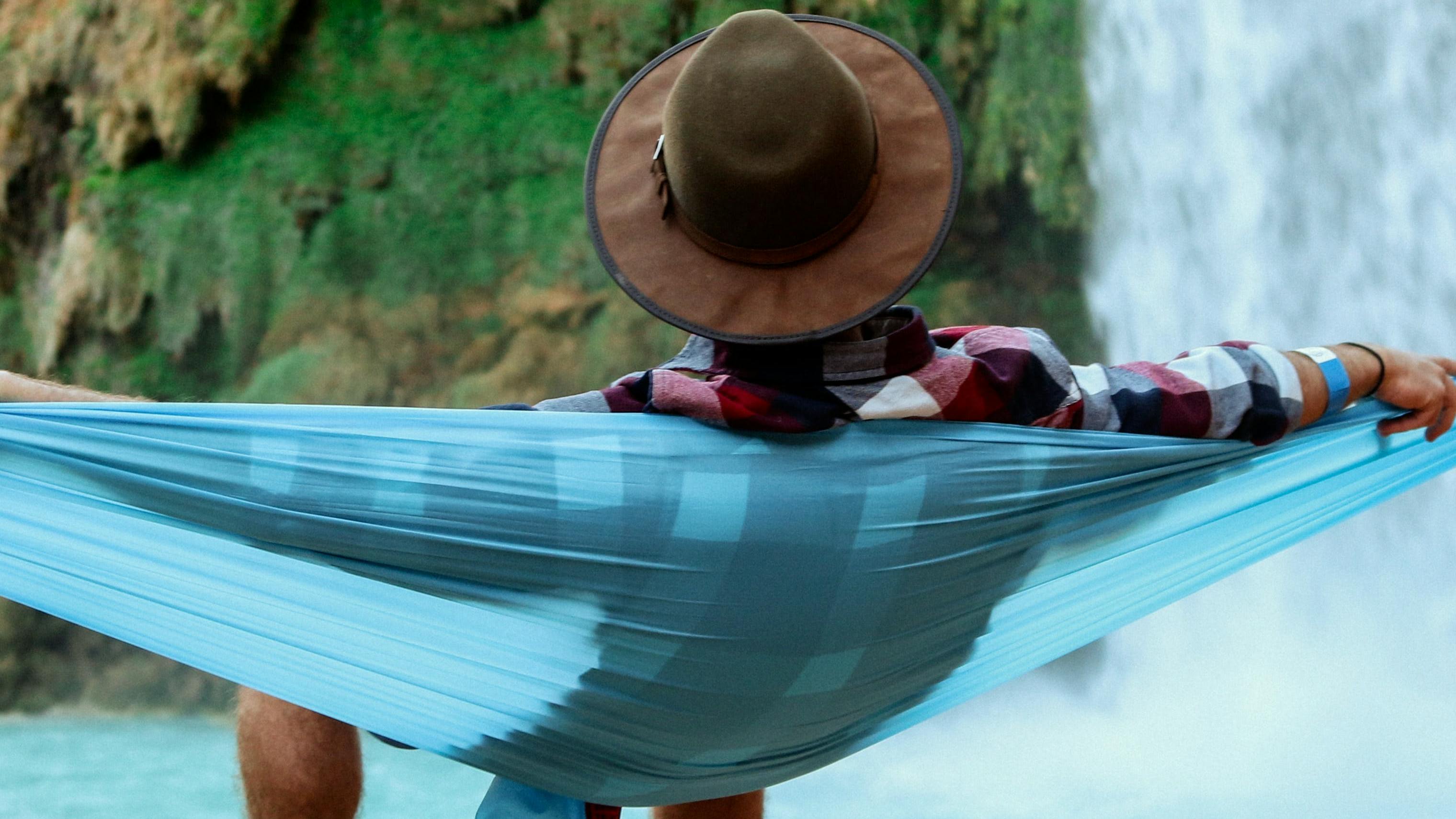 A man sitting in a hammock looking at a waterfall.