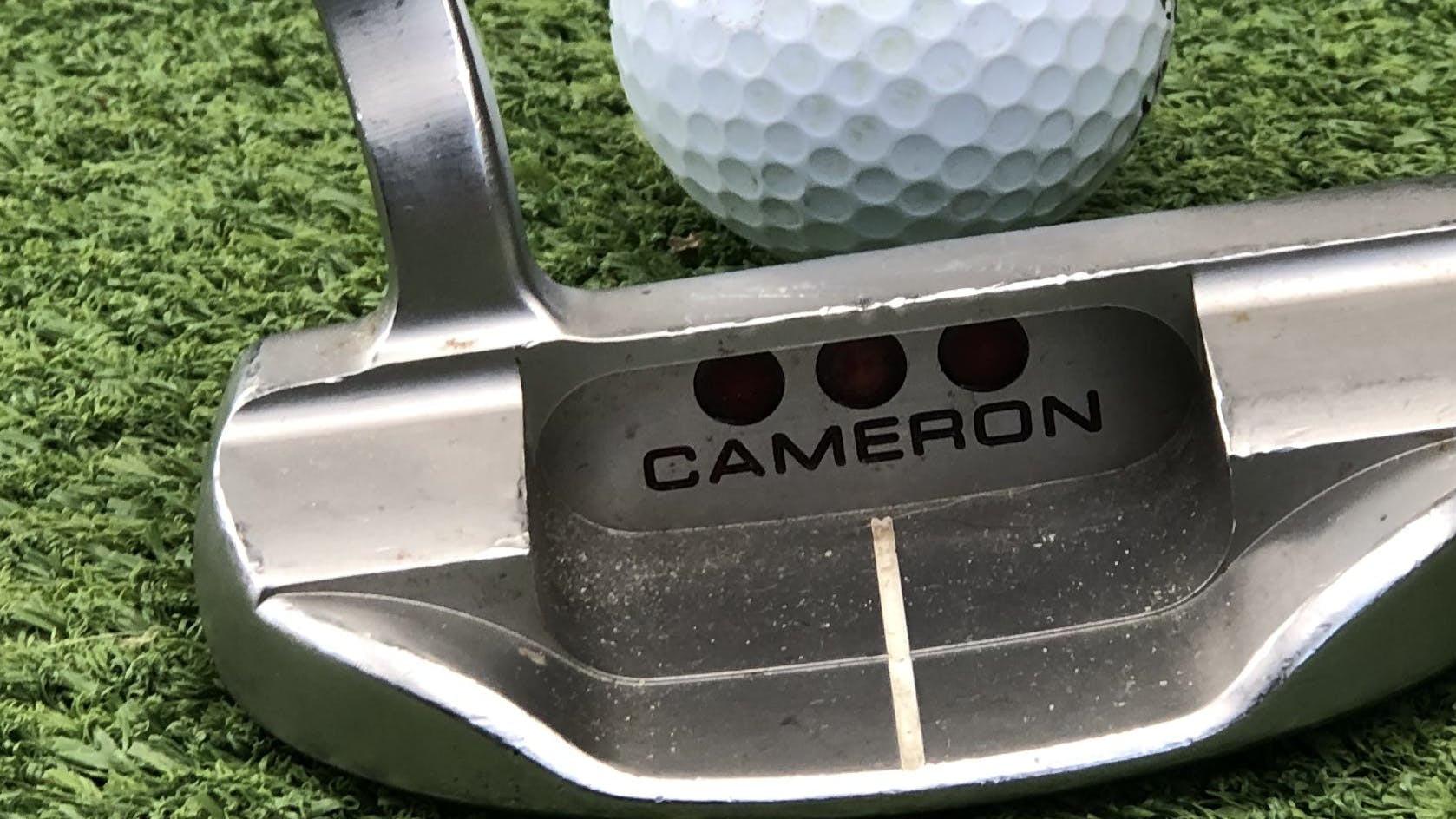 The Scotty Cameron Special Select Fastback 1.5 Putter in front of a golf ball.