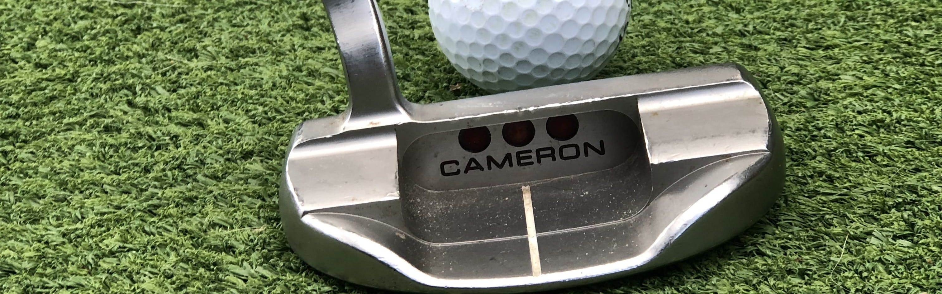 The Scotty Cameron Special Select Fastback 1.5 Putter in front of a golf ball.