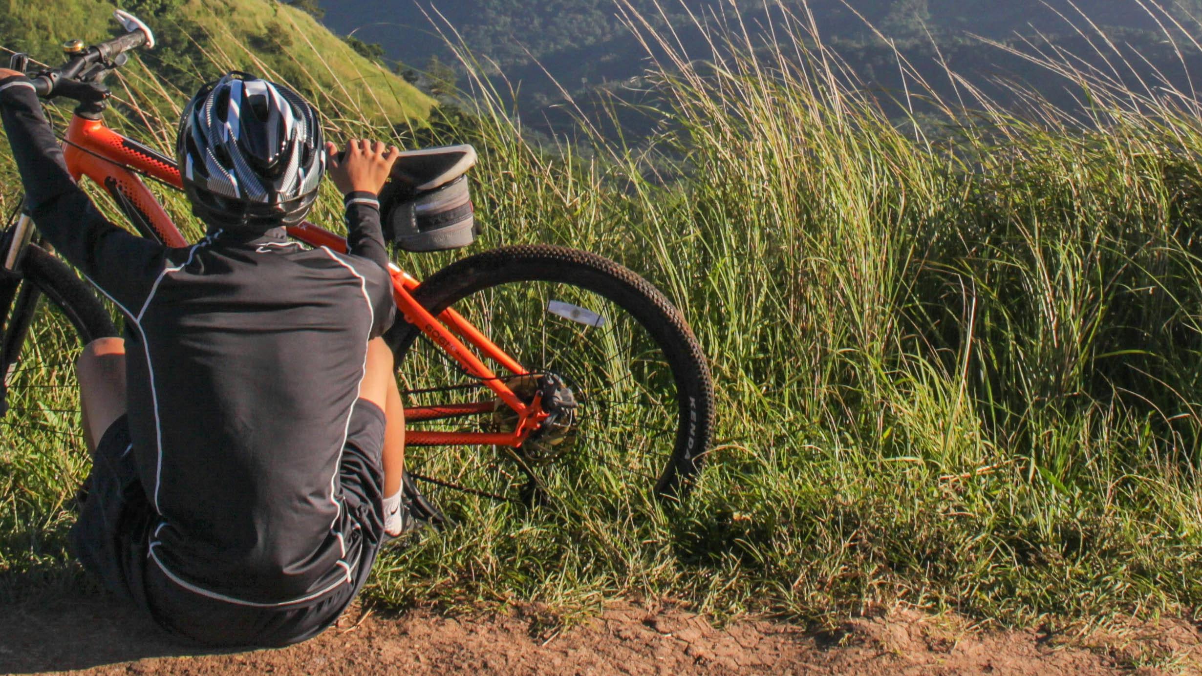 A cyclist sits on the ground next to his orange mountain bike