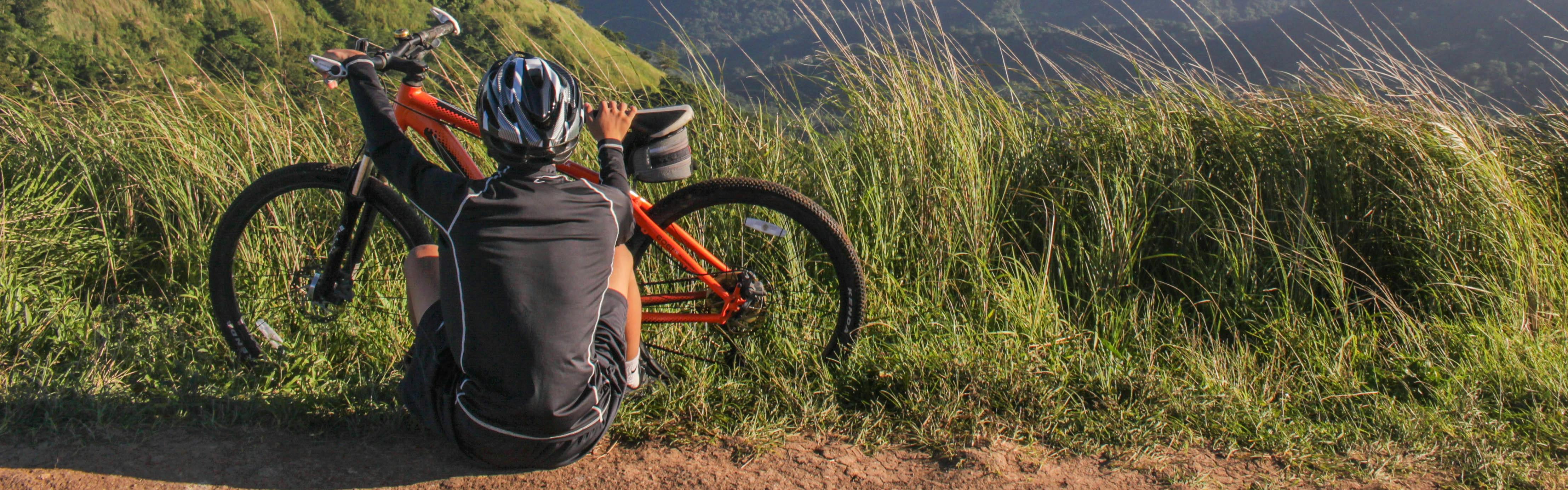 A cyclist sits on the ground next to his orange mountain bike