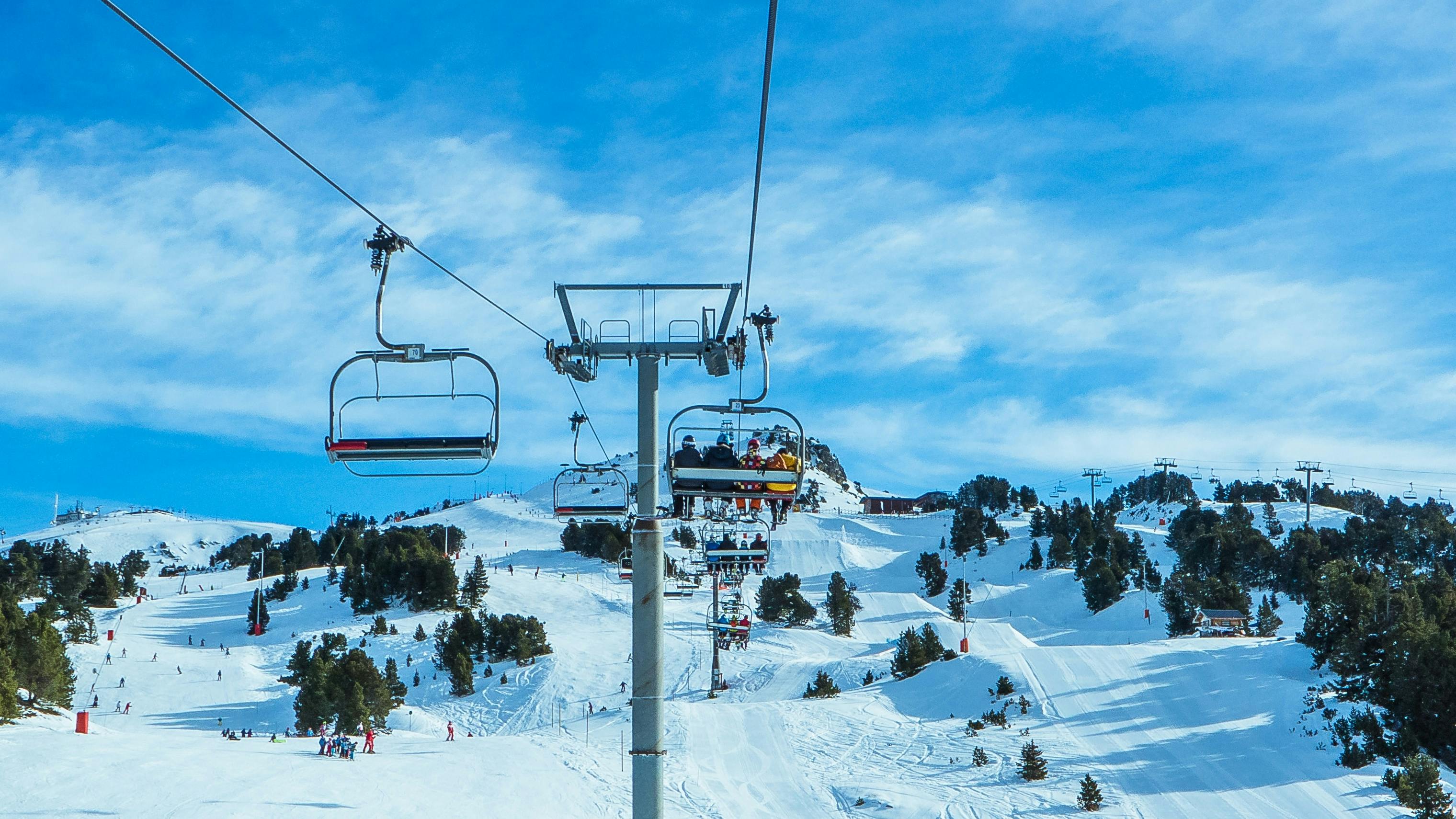 A chair lift against a blue sky and a snowy mountain