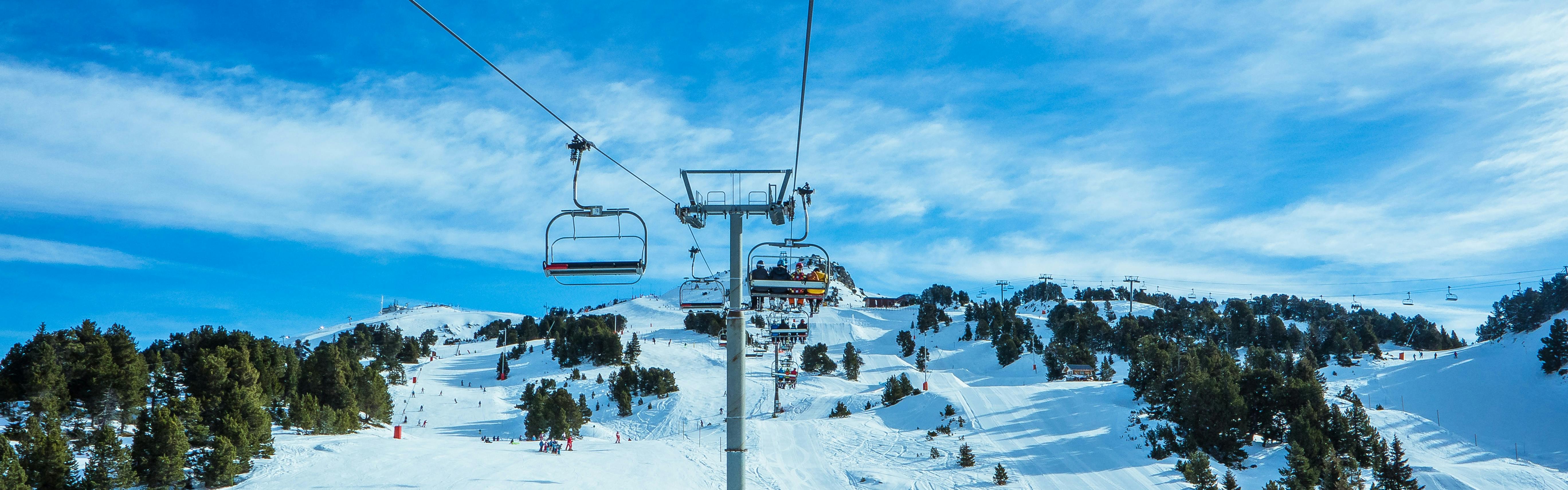 A chair lift against a blue sky and a snowy mountain