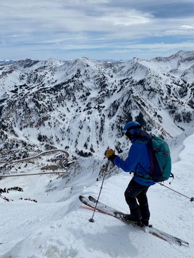 A skier at the top of a chute wearing his ski backpack and helmet.