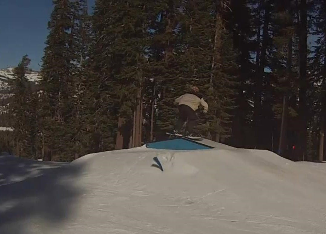 A snowboarder hitting a box feature in a terrain park. 