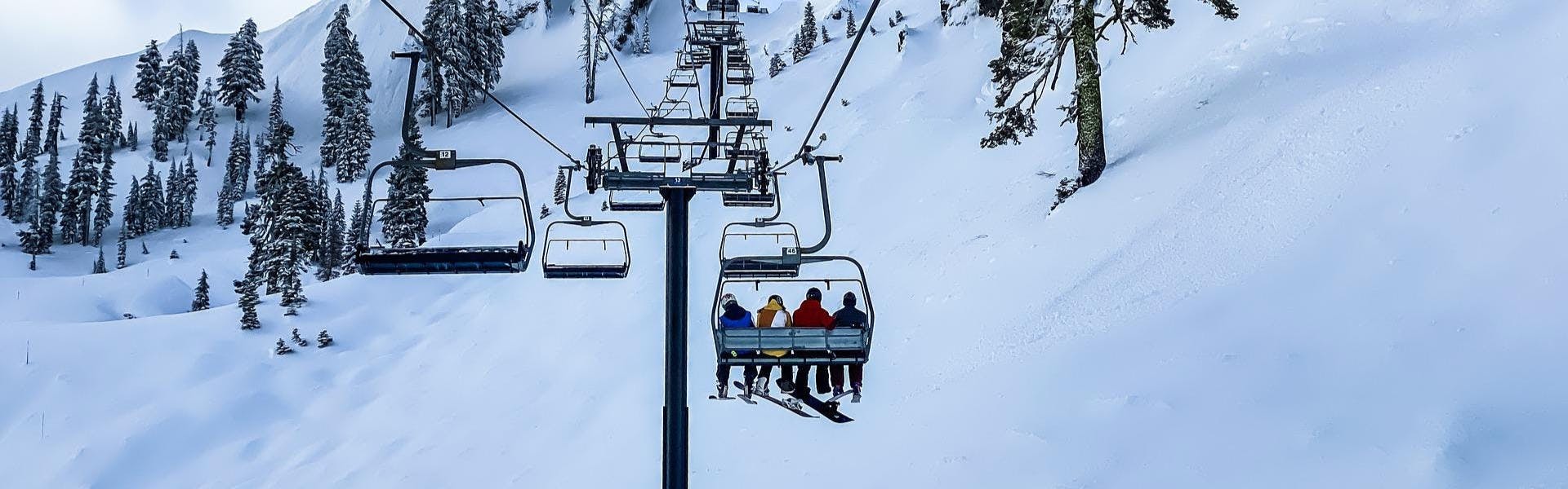 Snowboarders and skier sit on a chairlift.