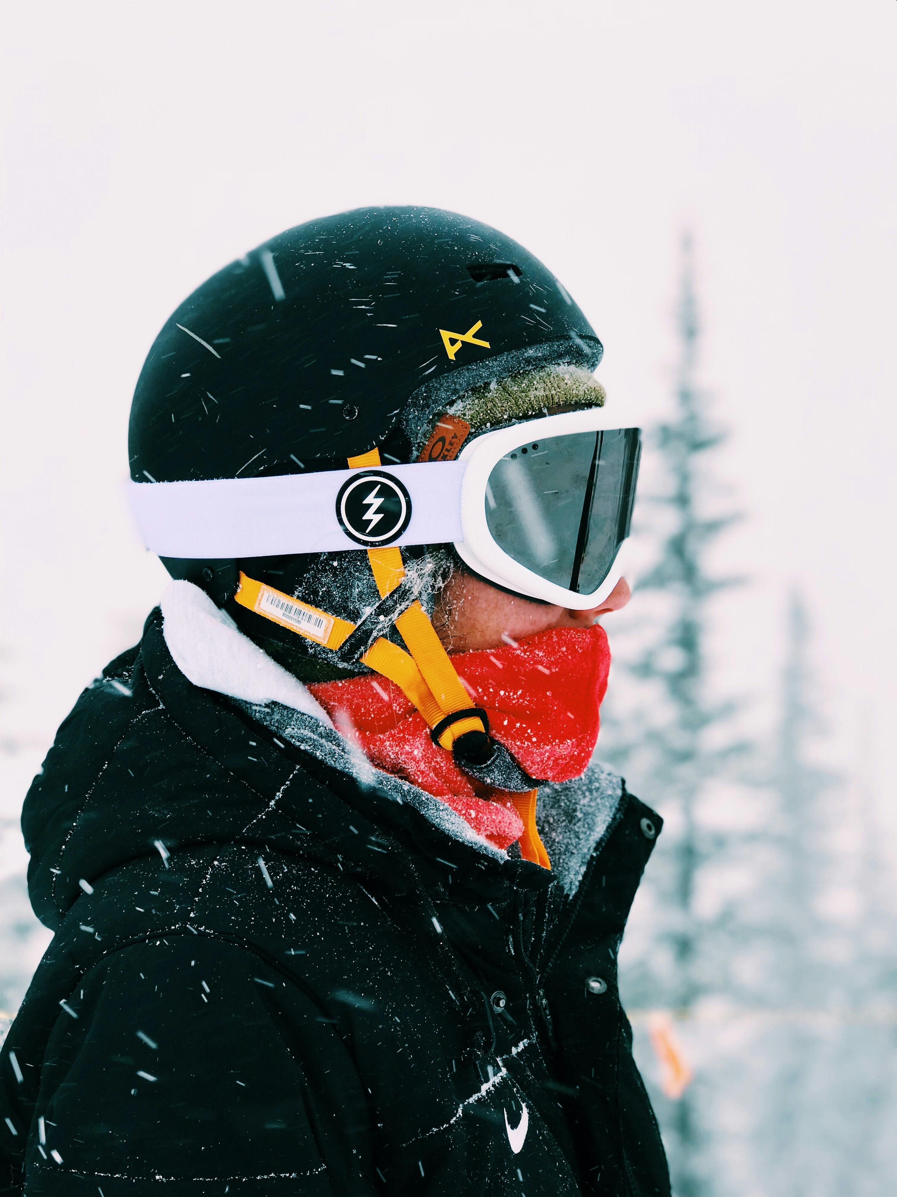 A person standing in the snow while wearing a snow helmet and goggles. 