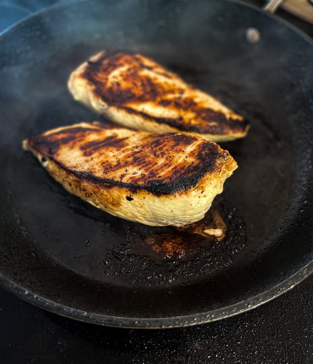 Two chicken breasts face down on a pan. 