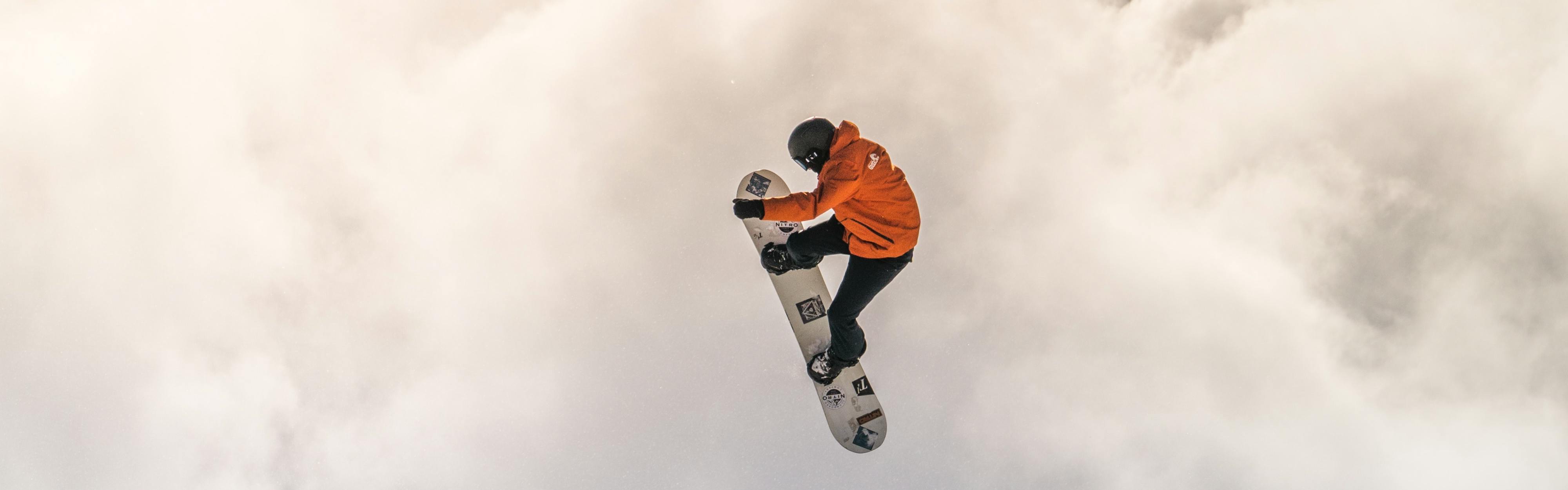 A snowboarder grabs his snowboard while in the air. 