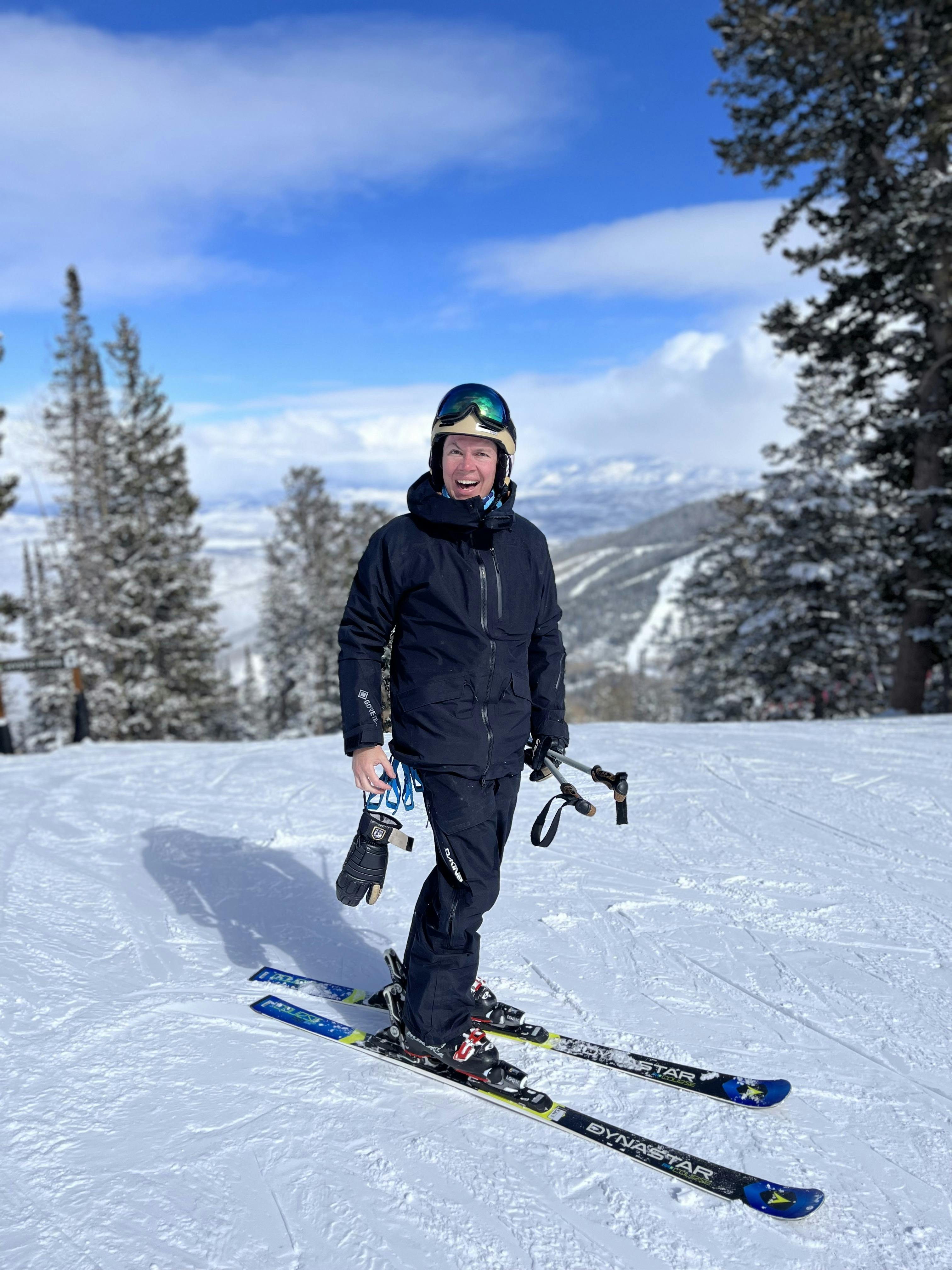 A skier standing on the slopes and smiling. 