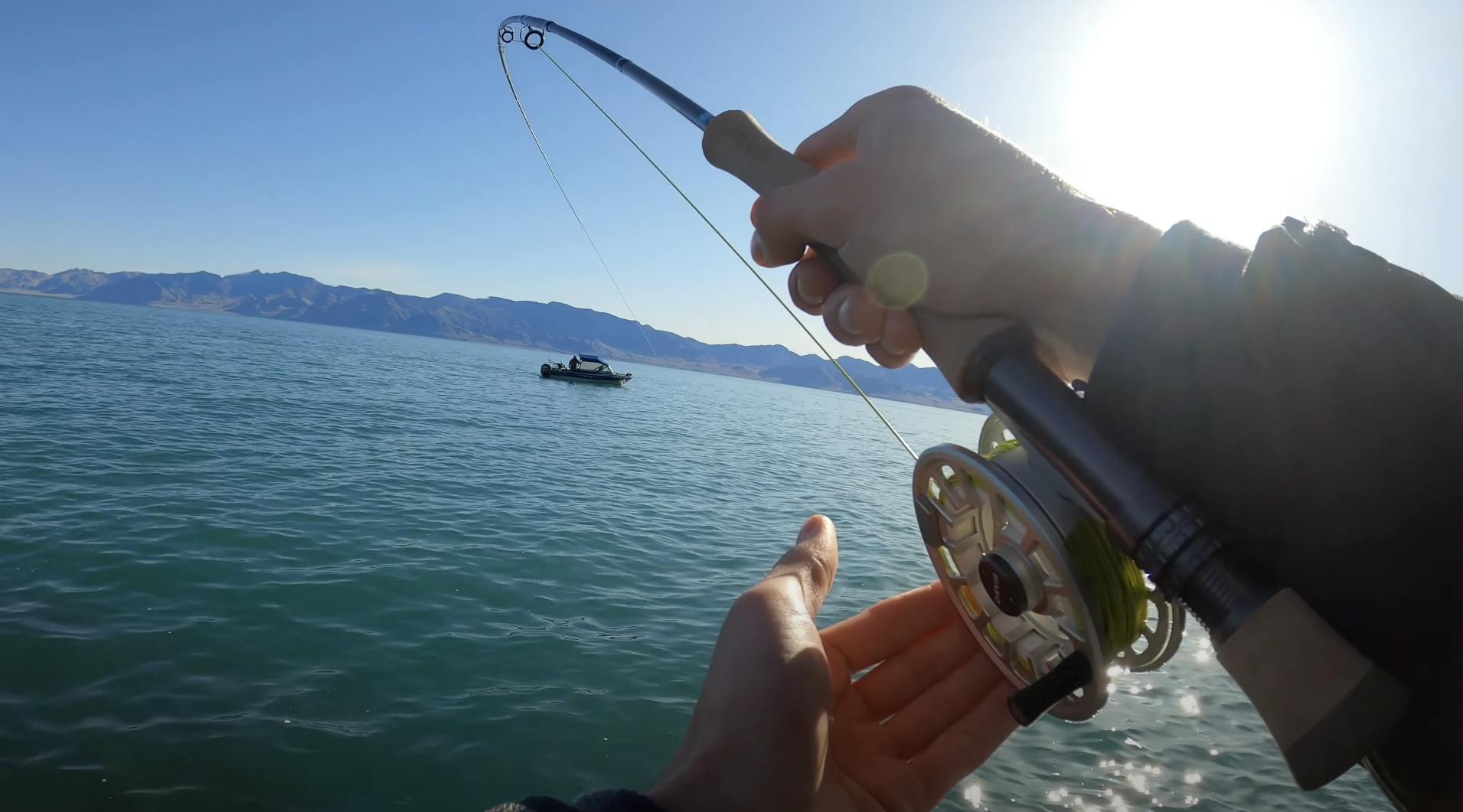 A fisherman using the Orvis Hydros Fly Reel to fish on a body of water.