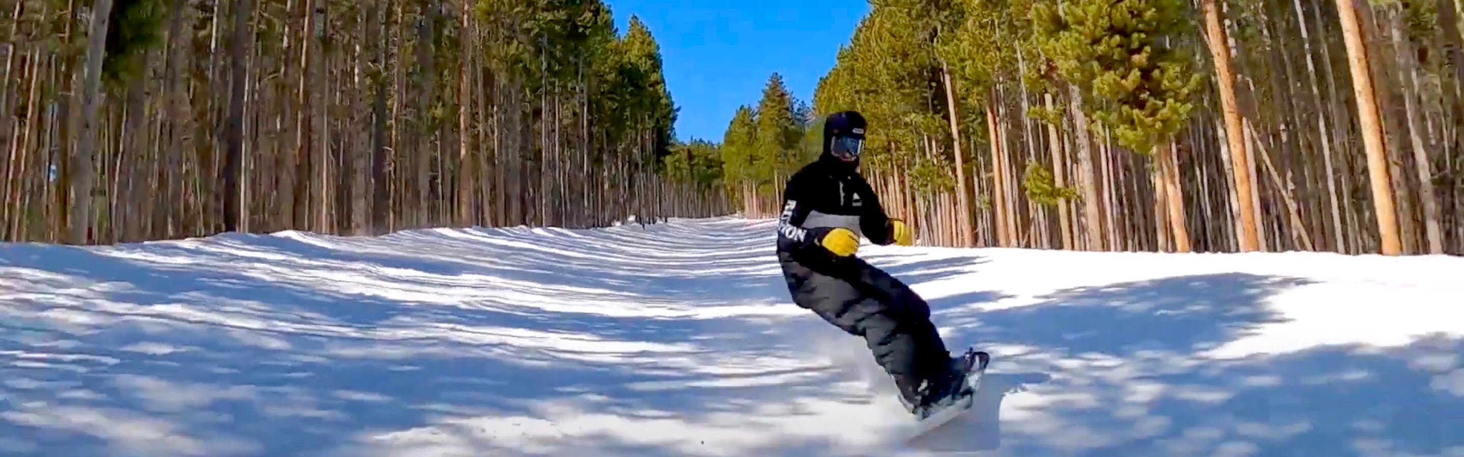 A screenshot of the YouTube video shows Bobby riding downhill in an open space between dense forest. The sky is a brilliant blue behind him.