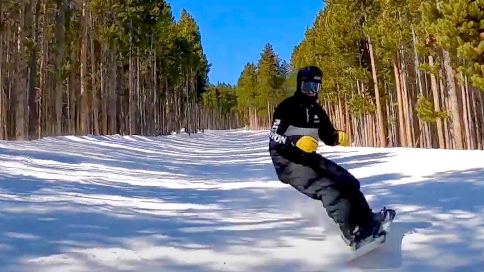 A screenshot of the YouTube video shows Bobby riding downhill in an open space between dense forest. The sky is a brilliant blue behind him.