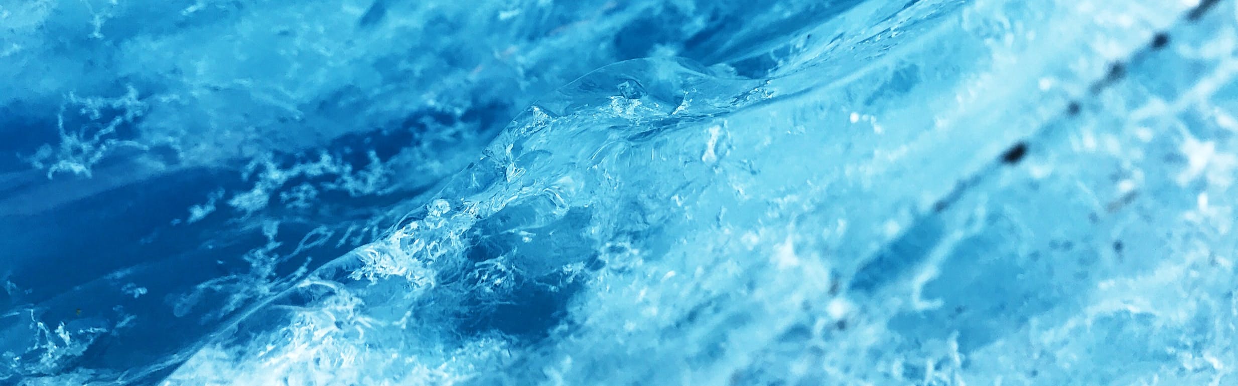 A close-up image of fractures within a block of blue-tinted ice.
