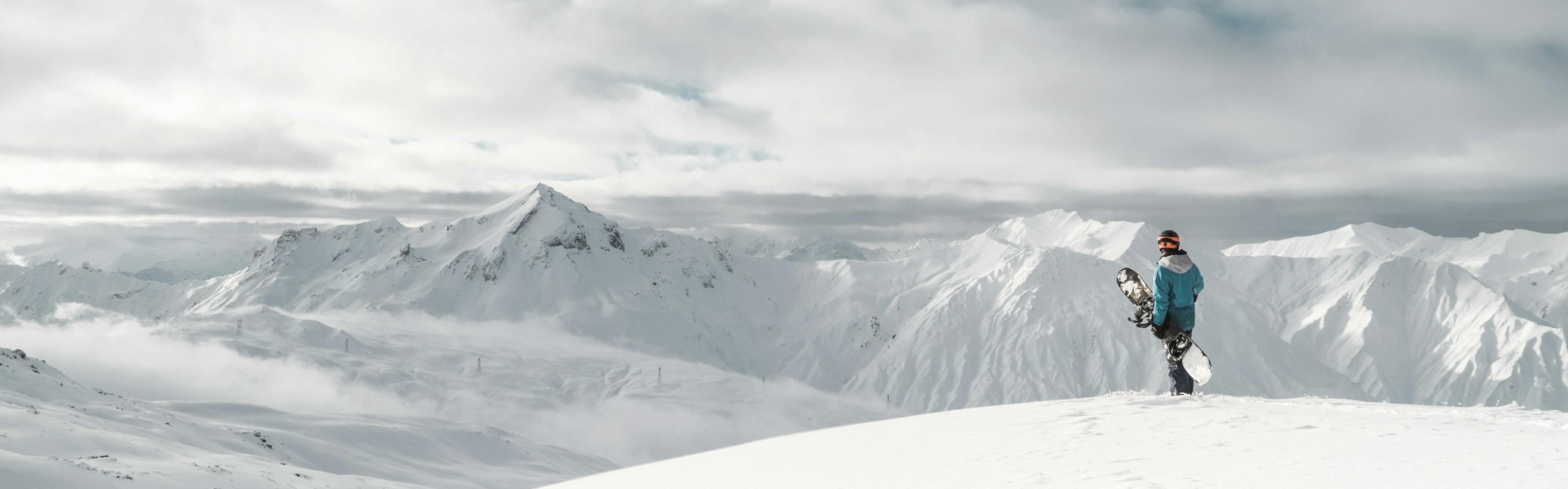 A snowboarder standing at the top of a snowy mountain. 