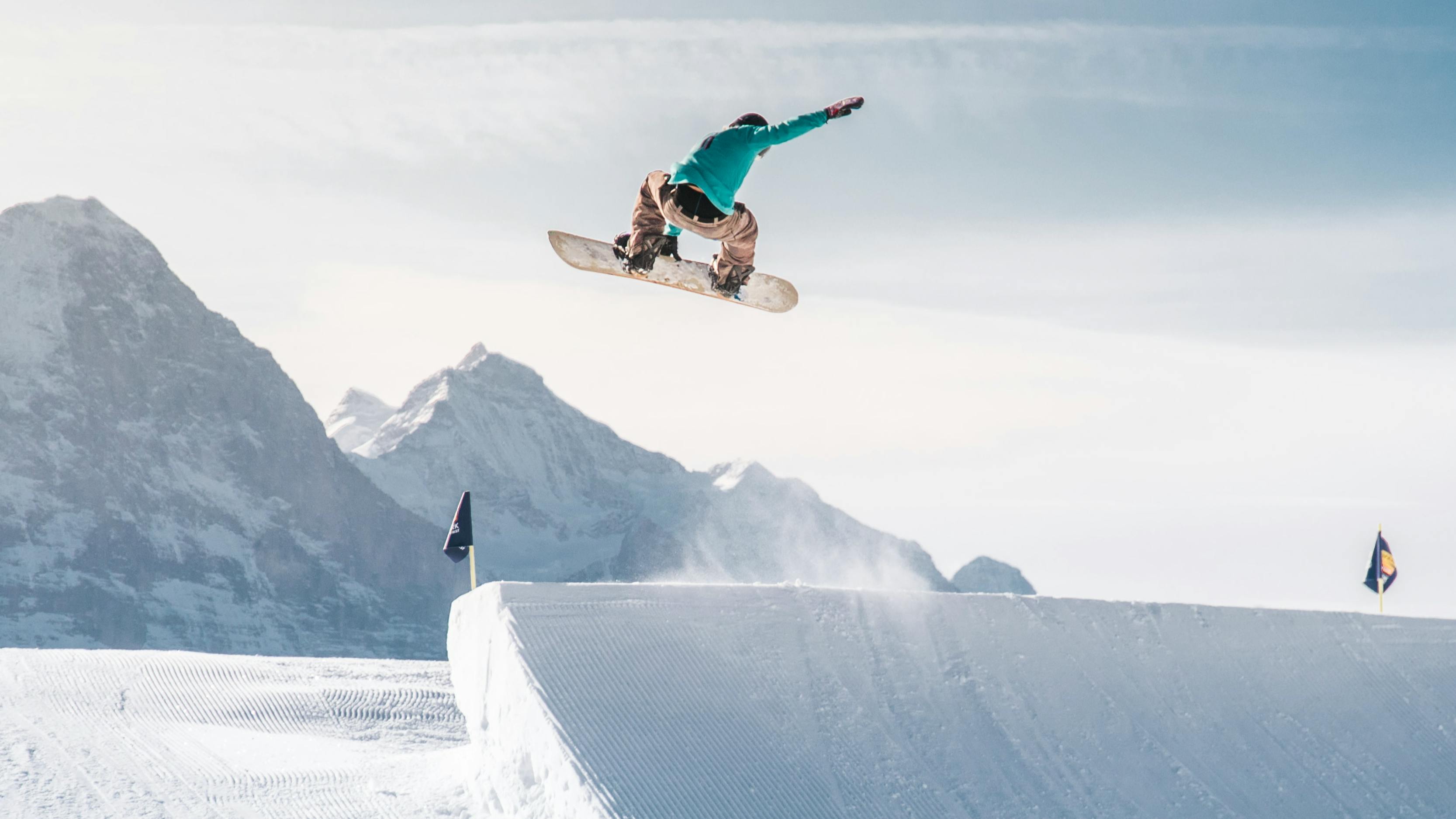 A man jumps off a jump at a ski resort on a snowboard. 